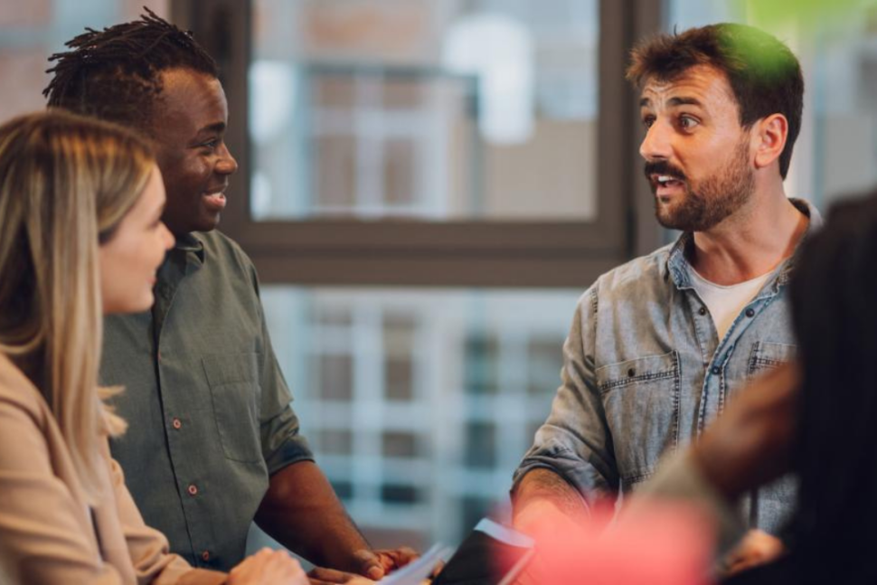 Een groep van 4 personen zitten op stoelen en zijn met elkaar in gesprek.